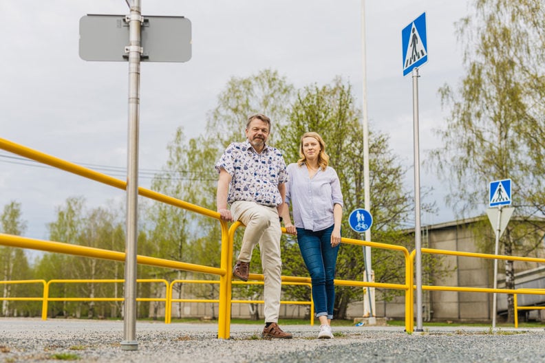 Anssi Hietanen ja Eeva Tuomi katsovat kameraan ja nojaavat aitaan.